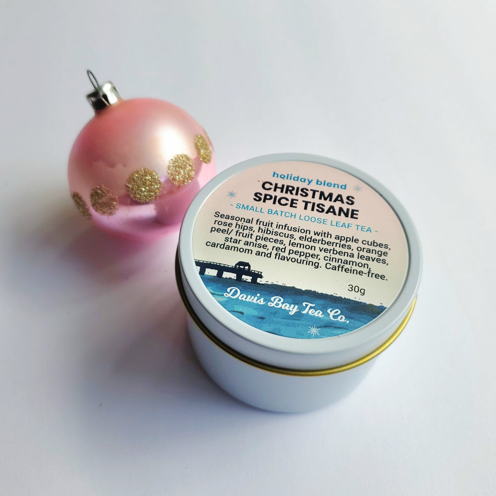 
                  
                    Tea tin labeled 'Christmas Spice Tisane' with a pink ornament on a light background
                  
                