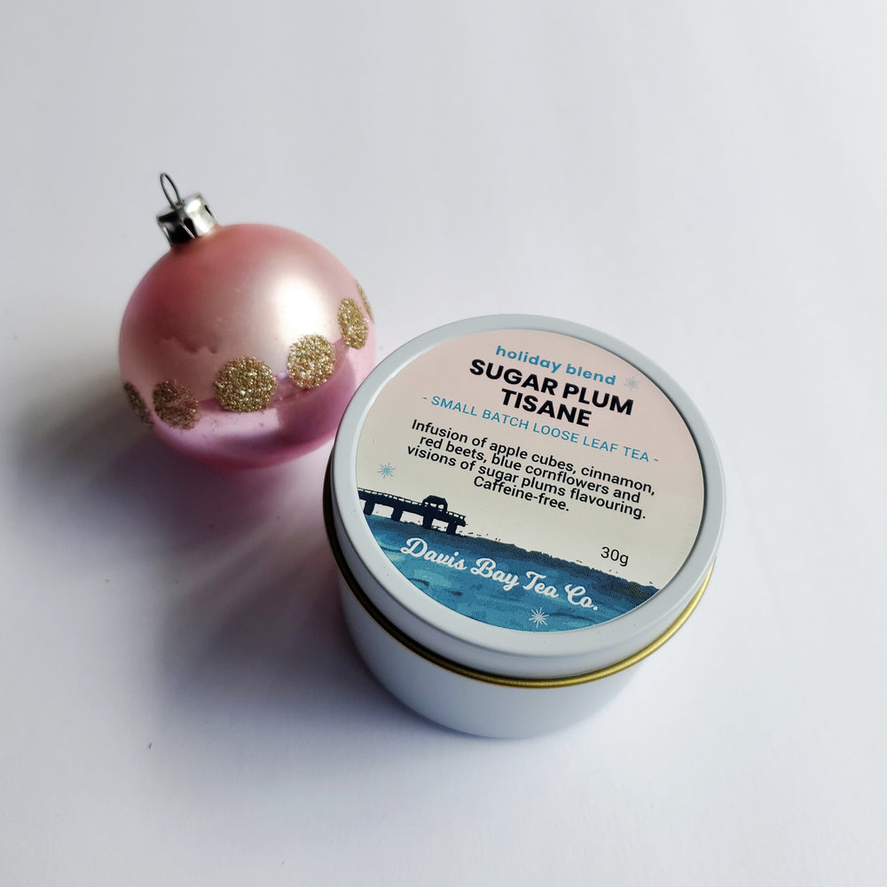 Tin of 'Sugar Plum Tisane' from Davis Bay Tea Co. with a pink ornament on a white background