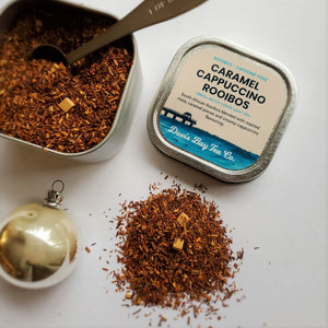 
                  
                    open tin of Caramel Cappuccino Rooibos tea with tea scoop and pile of tea on display
                  
                