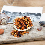 Carrot cake fruit tisane loose leaf tea blend in half seashell on driftwood with seashells and vintage photo.