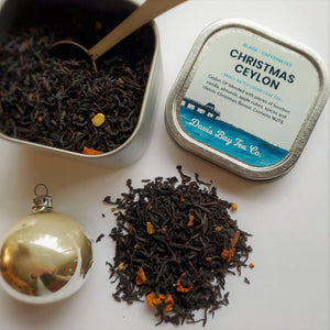 
                  
                    open tin of Christmas Ceylon tea with scoop and pile of tea on display
                  
                