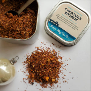 
                  
                    open tin of Christmas Rooibos tea with scoop and pile of tea on display
                  
                