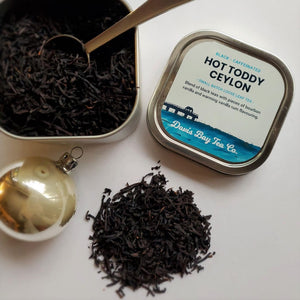 
                  
                    open tin of Hot Toddy Ceylon tea with scoop and pile of tea 
                  
                