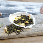 Green Jasmine Loose leaf tea with jasmine flowers in half seashell on driftwood with vintage black and white photo.